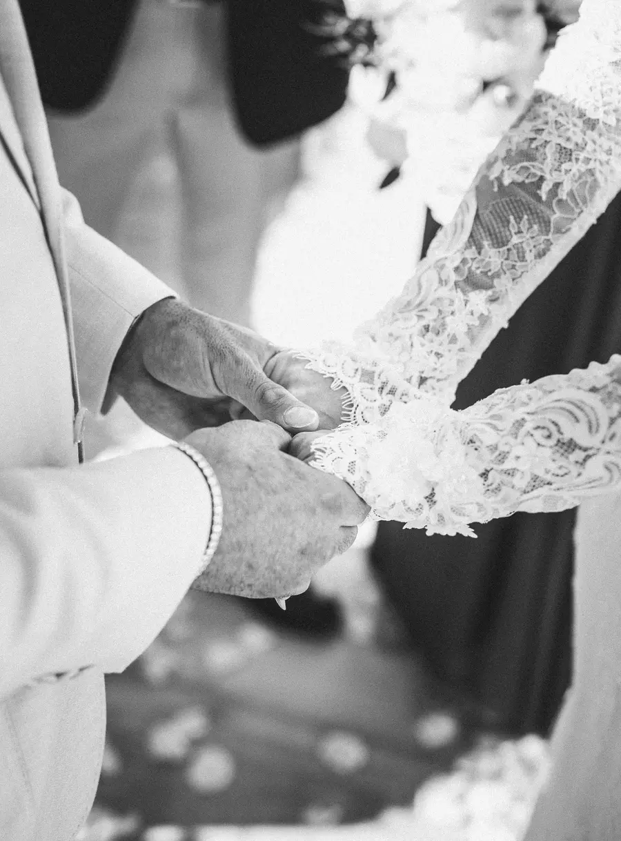 Dettaglio in bianco e nero della mano della sposa stretta da quella del padre