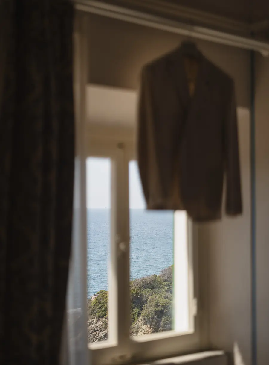 Giacca dello sposo appesa alla finestra con vista mare, preparativi a Villa Parisi