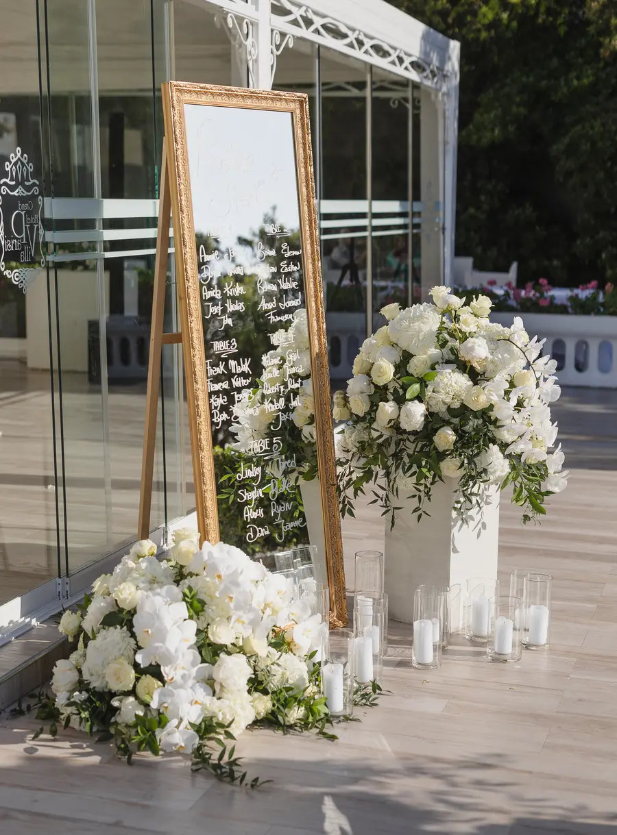 Tableau de mariage su specchio con cornice dorata, fiori bianchi e candele