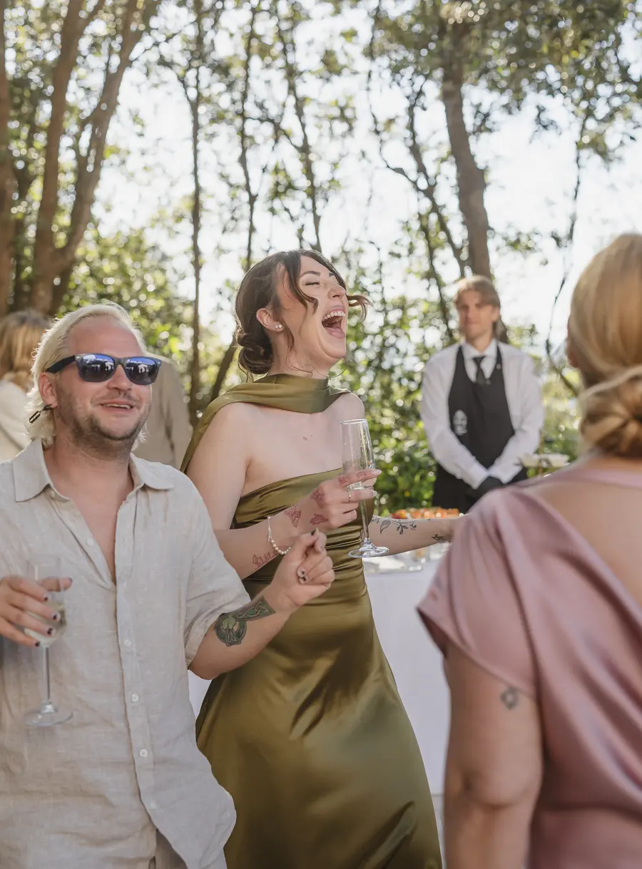 Ospiti che ridono e brindano con il calice durante l'aperitivo all'aperto