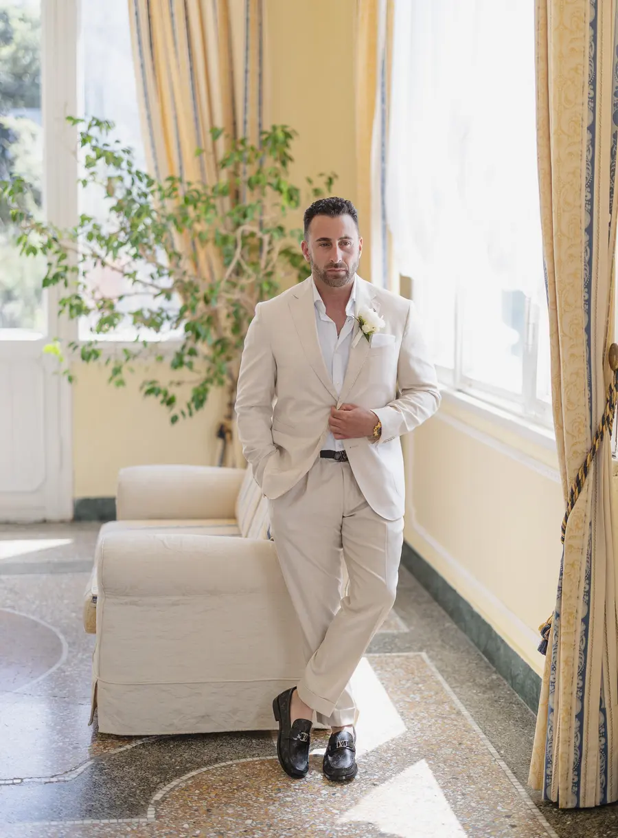 Ritratto dello sposo in abito beige nella veranda di Villa Parisi a Castiglioncello