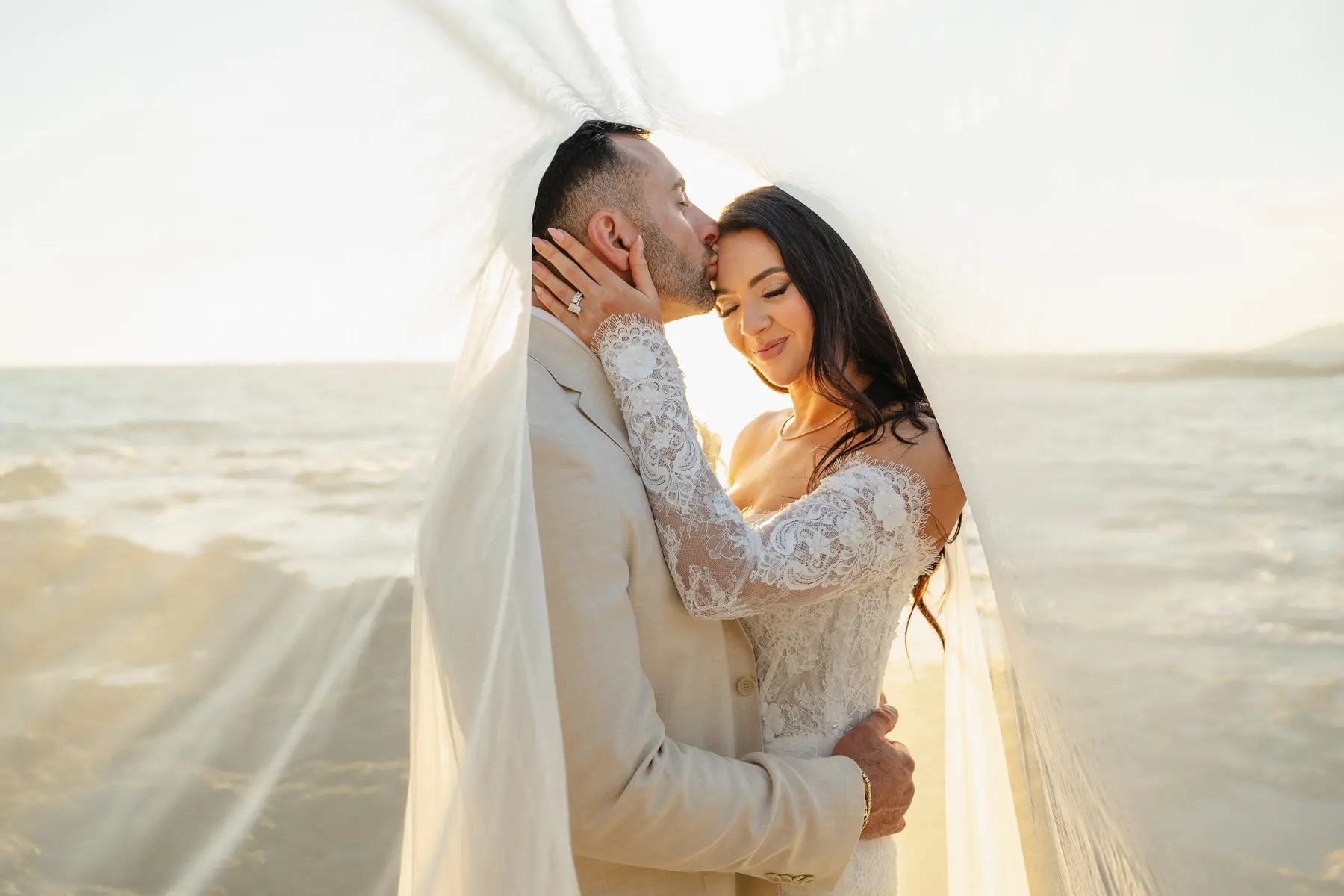 Servizio fotografico di matrimonio a Castiglioncello: sposi abbracciati sotto il velo al tramonto