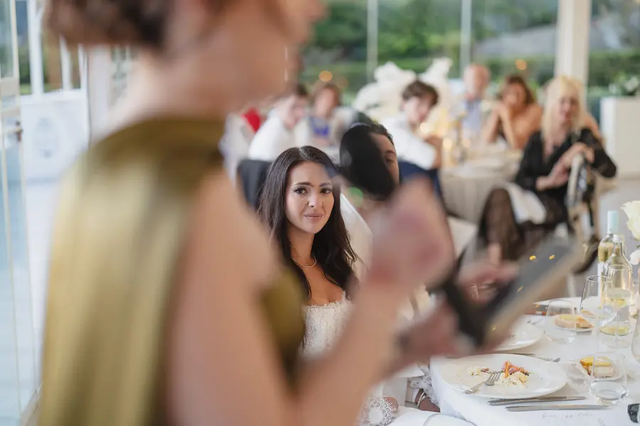 Un'invitata legge il suo discorso durante la cena mentre la sposa ascolta