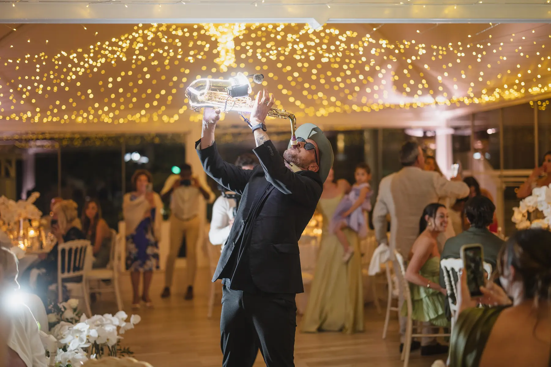 Il sassofonista con sax luminoso anima la cena di nozze sotto le luci del padiglione