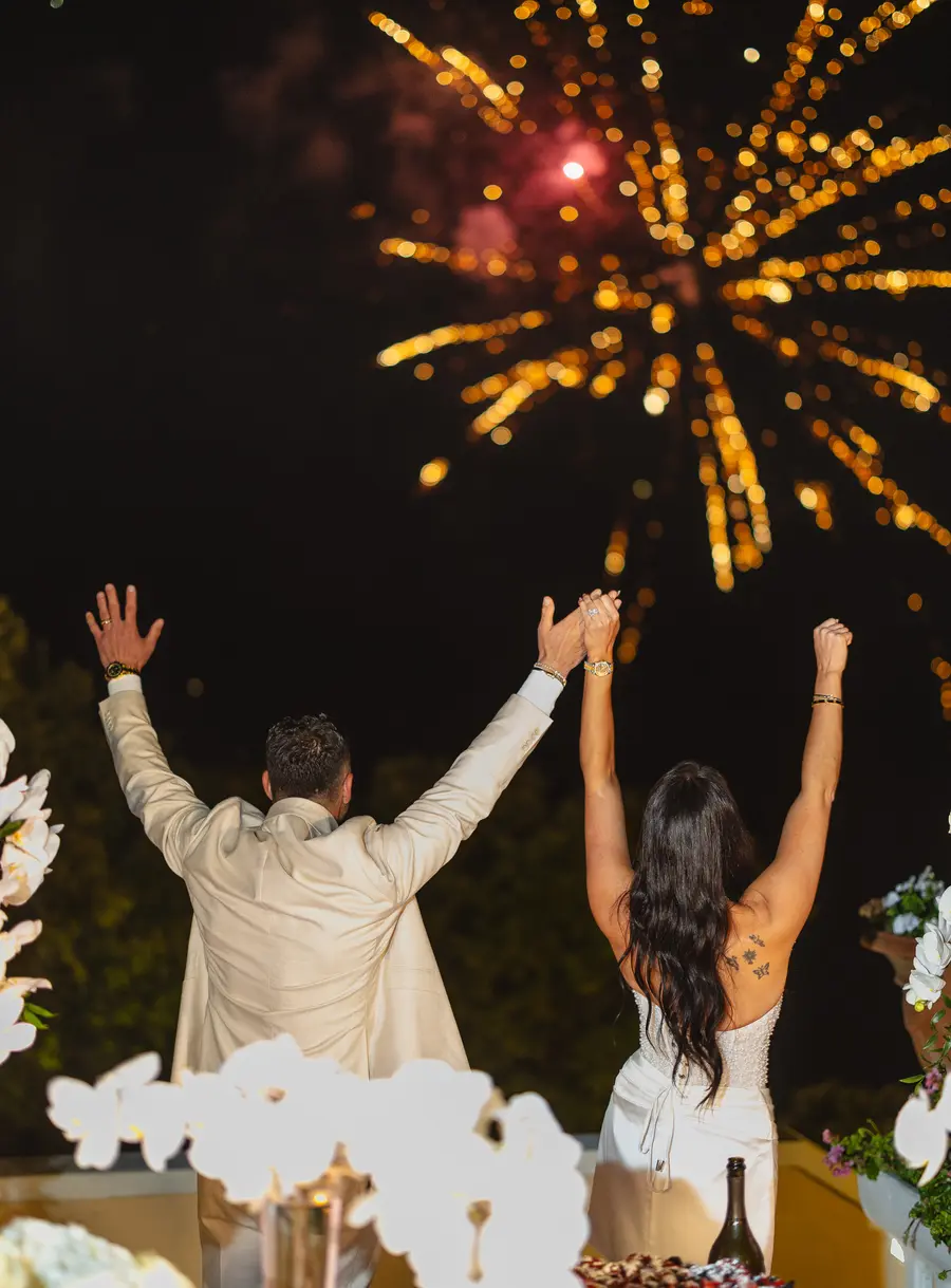 Frank e Nicolette di spalle con le braccia alzate sotto i fuochi d'artificio a Villa Parisi